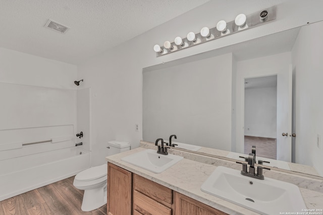 full bathroom with shower / tub combination, a textured ceiling, wood-type flooring, vanity, and toilet