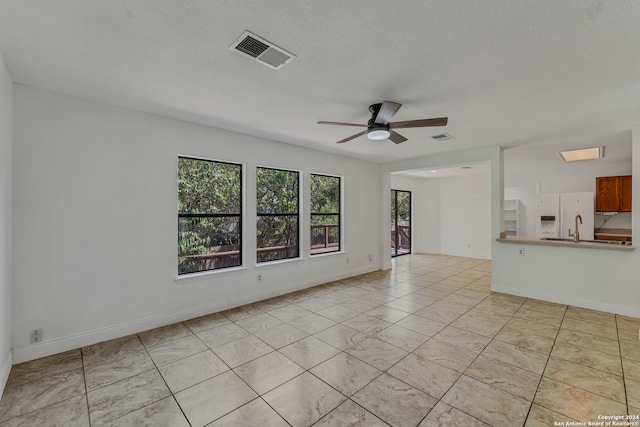 unfurnished living room featuring a textured ceiling, ceiling fan, and light tile patterned floors