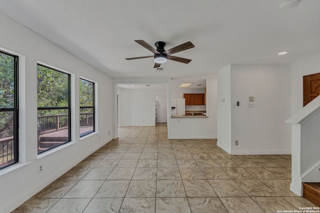 unfurnished living room with a textured ceiling and ceiling fan