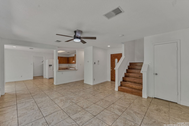 unfurnished living room featuring ceiling fan, a textured ceiling, and sink