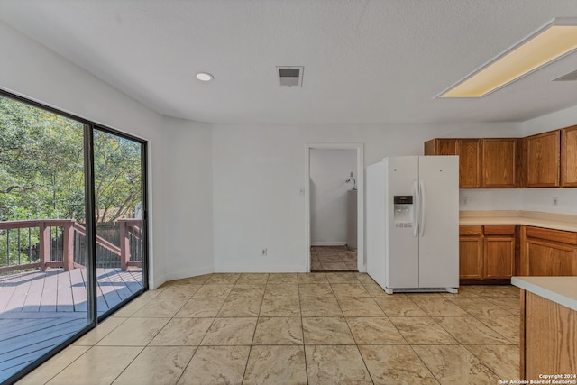 kitchen with a textured ceiling and white fridge with ice dispenser