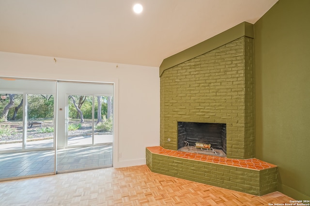 living room featuring a brick fireplace, light parquet flooring, and vaulted ceiling