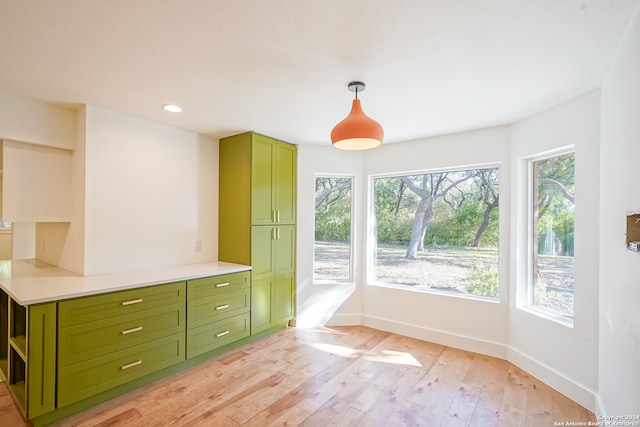 interior space featuring green cabinetry, pendant lighting, light wood-type flooring, and plenty of natural light