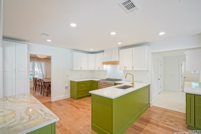 kitchen featuring light hardwood / wood-style flooring, green cabinets, stainless steel gas range, sink, and white cabinets