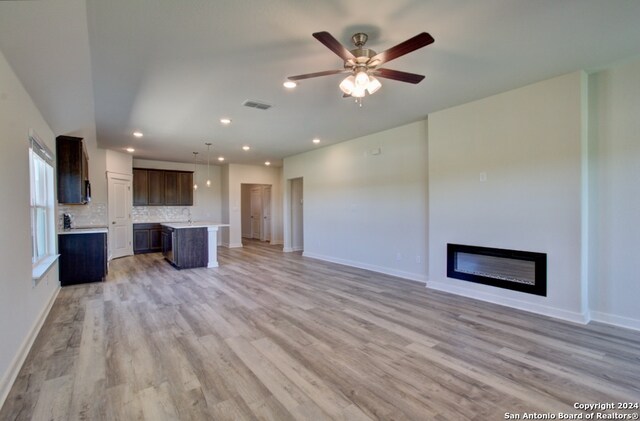 unfurnished living room featuring ceiling fan and light hardwood / wood-style flooring