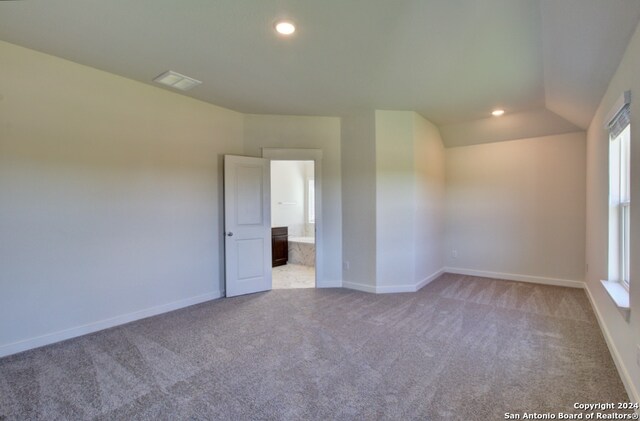 empty room featuring light carpet and vaulted ceiling