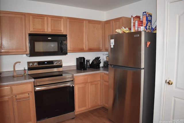 kitchen with appliances with stainless steel finishes and light hardwood / wood-style floors