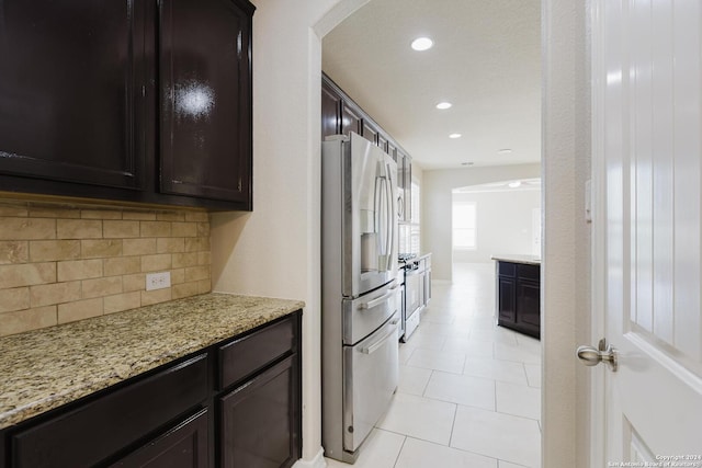 kitchen featuring light stone countertops, dark brown cabinetry, backsplash, and stainless steel appliances