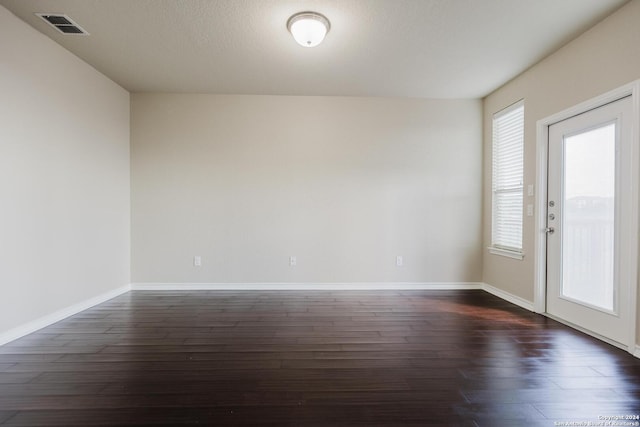 spare room featuring dark wood-type flooring and a textured ceiling