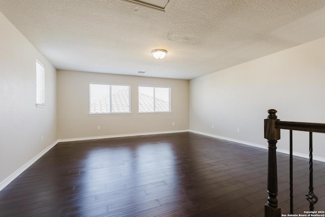 spare room featuring dark hardwood / wood-style flooring and a textured ceiling