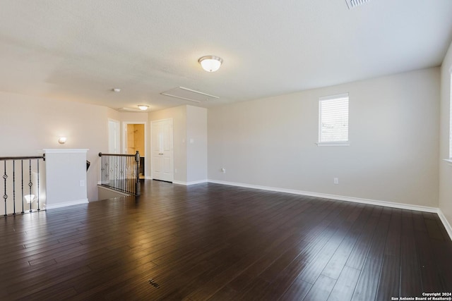 spare room featuring a textured ceiling and dark hardwood / wood-style flooring