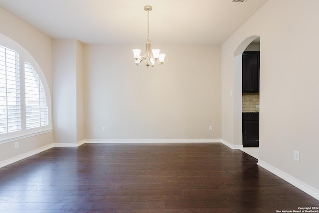 empty room with a chandelier and dark hardwood / wood-style flooring