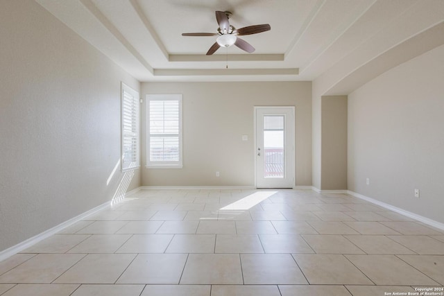 spare room with ceiling fan, a raised ceiling, and light tile patterned floors