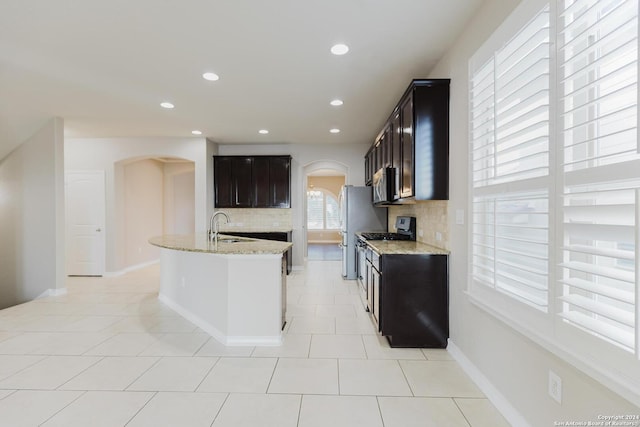 kitchen with stainless steel appliances, sink, light stone counters, and decorative backsplash