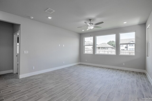 empty room with ceiling fan, a textured ceiling, and light hardwood / wood-style floors