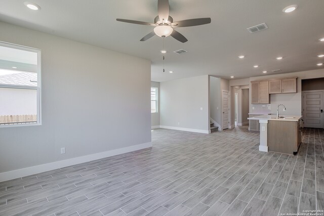 kitchen featuring a kitchen island with sink, light wood-type flooring, sink, and ceiling fan