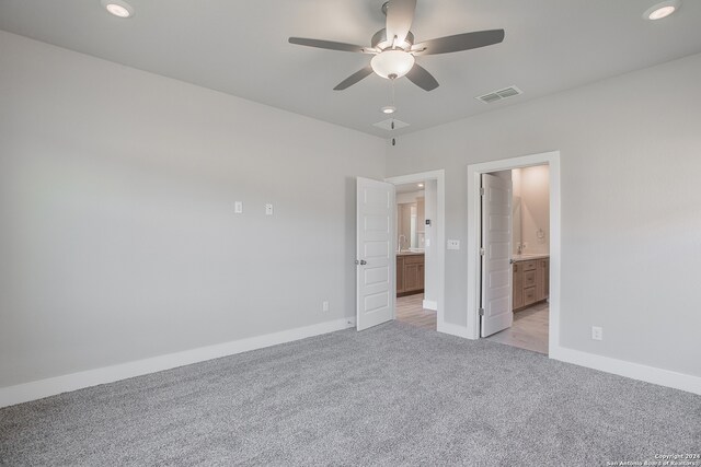 unfurnished bedroom with ensuite bath, ceiling fan, and light colored carpet