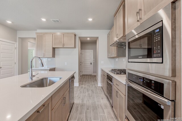 kitchen with light hardwood / wood-style flooring, light brown cabinetry, sink, and stainless steel appliances