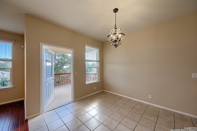 spare room featuring an inviting chandelier and light tile patterned floors