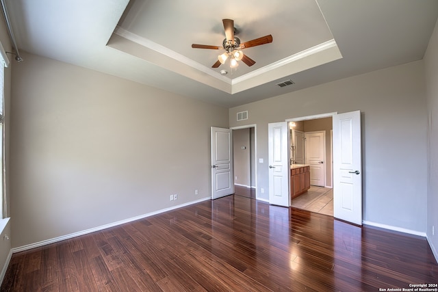 unfurnished bedroom with ceiling fan, a raised ceiling, and dark hardwood / wood-style flooring