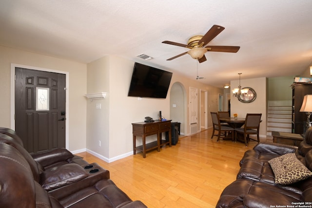 living room with light hardwood / wood-style floors and ceiling fan with notable chandelier