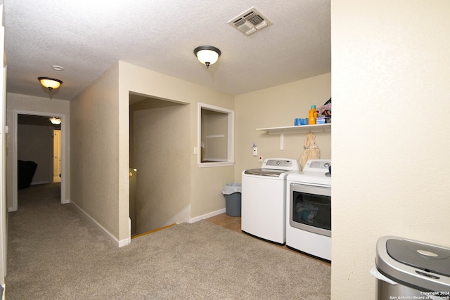 laundry area with light carpet, a textured ceiling, and washer and clothes dryer