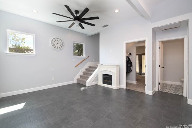 unfurnished living room featuring ceiling fan and a fireplace