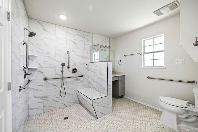 bathroom with vanity, toilet, a tile shower, and tile patterned floors