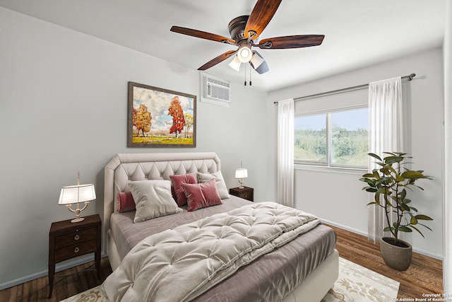 bedroom featuring a wall unit AC, dark hardwood / wood-style floors, and ceiling fan