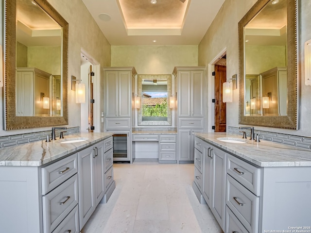 bathroom with vanity, backsplash, and a tray ceiling