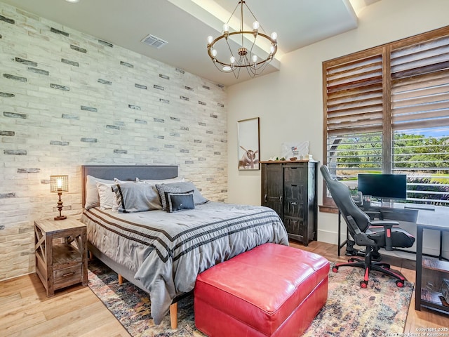 bedroom with light hardwood / wood-style floors and an inviting chandelier