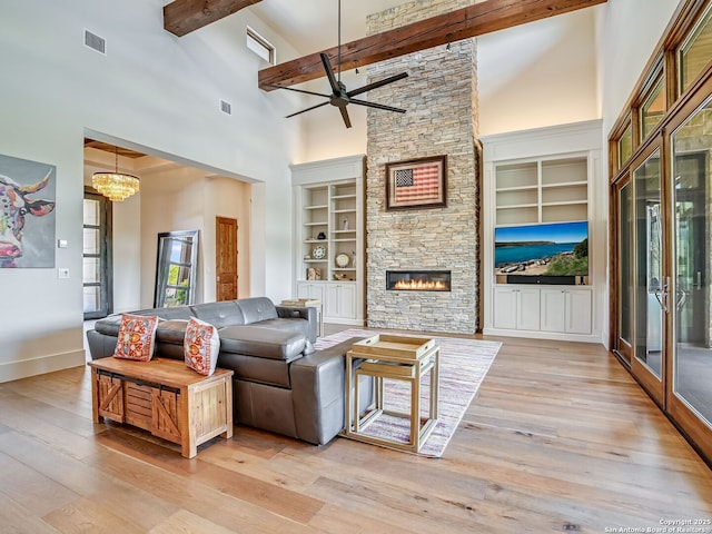 living room featuring built in features, beam ceiling, a towering ceiling, and a fireplace