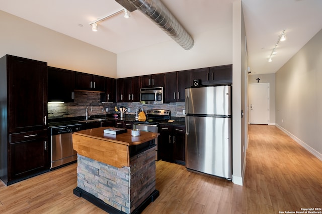 kitchen with sink, a center island, stainless steel appliances, tasteful backsplash, and light wood-type flooring