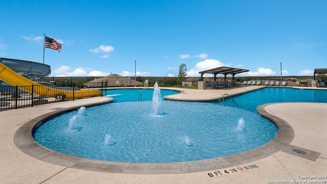 view of swimming pool featuring a patio area, a water slide, and pool water feature