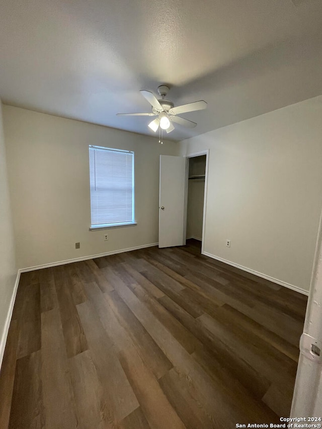 unfurnished bedroom featuring dark wood-type flooring, ceiling fan, and a closet