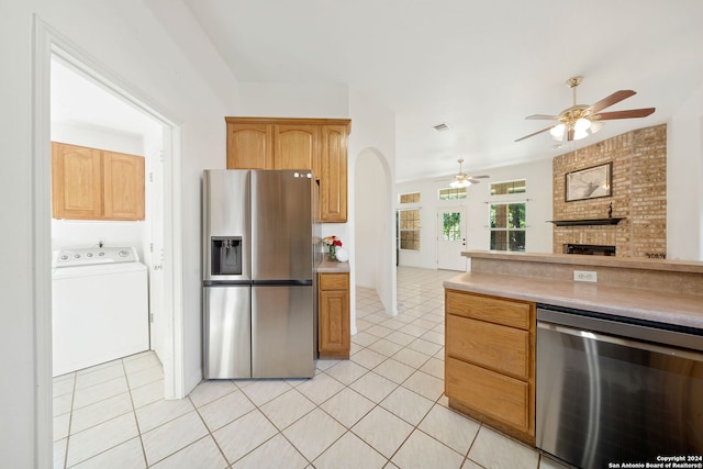 kitchen featuring a fireplace, appliances with stainless steel finishes, light tile patterned floors, and washer / dryer