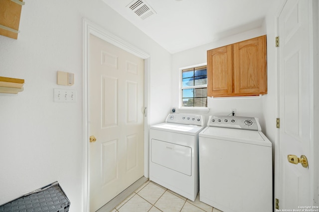 laundry room featuring washer and clothes dryer, cabinets, and light tile patterned floors