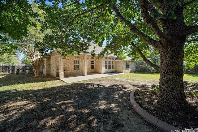 rear view of house featuring a lawn and a patio area