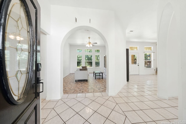 tiled foyer entrance with ceiling fan and a healthy amount of sunlight