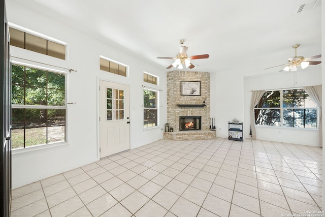 unfurnished living room with plenty of natural light, light tile patterned flooring, and a brick fireplace