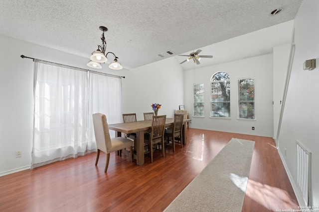 dining room with dark wood-type flooring, a textured ceiling, and ceiling fan with notable chandelier