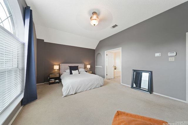 bedroom featuring ceiling fan, light carpet, vaulted ceiling, and ensuite bathroom