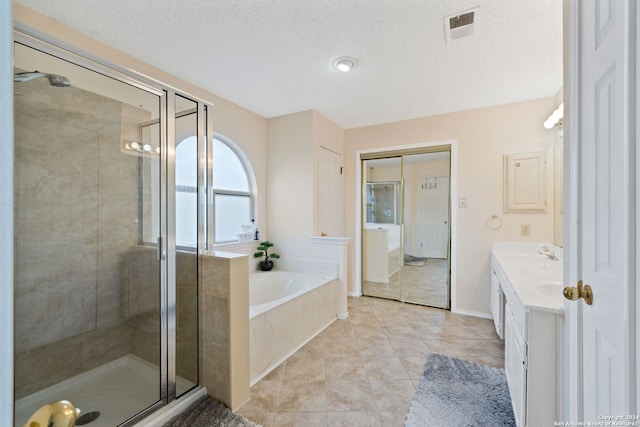 bathroom with vanity, independent shower and bath, a textured ceiling, and tile patterned flooring