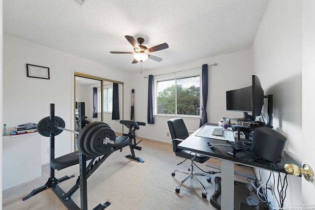 carpeted office space with a textured ceiling and ceiling fan