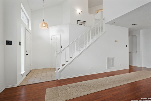 entrance foyer featuring hardwood / wood-style floors, a textured ceiling, and high vaulted ceiling