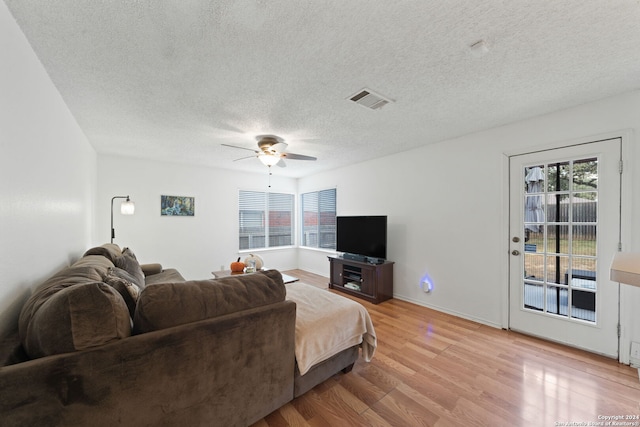 living room with light hardwood / wood-style flooring, a textured ceiling, and ceiling fan