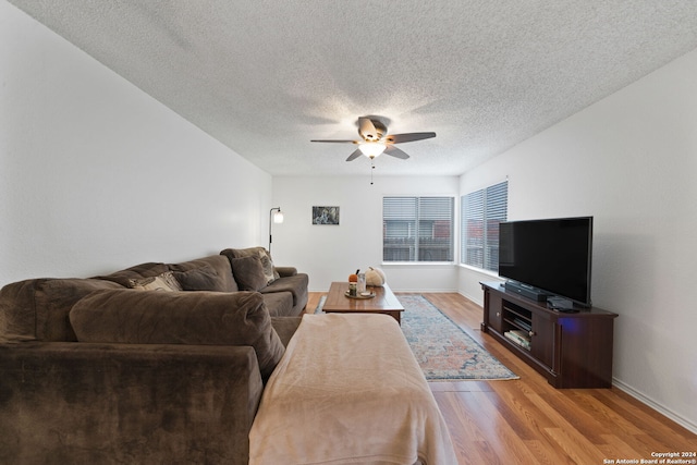 living room with a textured ceiling, light hardwood / wood-style floors, and ceiling fan