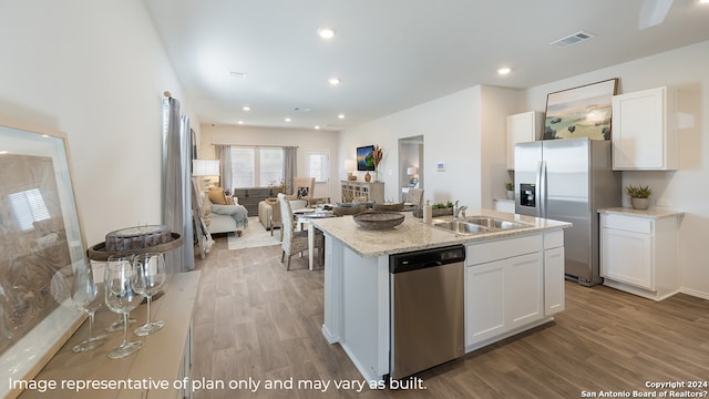 kitchen featuring sink, an island with sink, stainless steel appliances, white cabinets, and hardwood / wood-style flooring