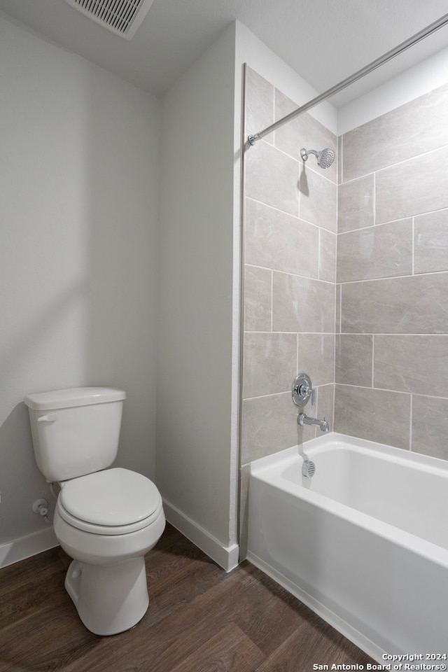 bathroom featuring toilet, tiled shower / bath combo, and hardwood / wood-style flooring