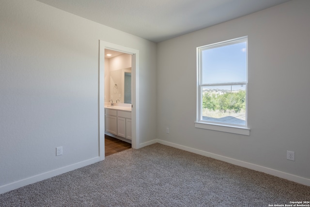 unfurnished bedroom featuring dark colored carpet and connected bathroom